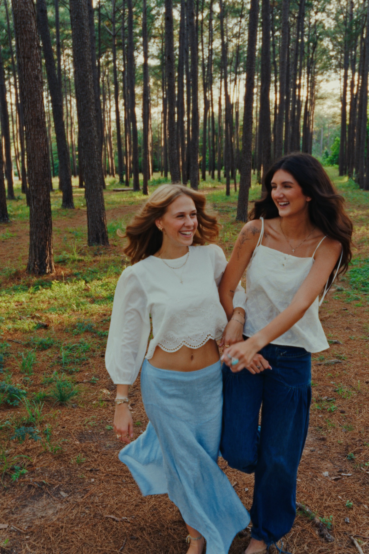 Two women walking through a sunlit pine forest
